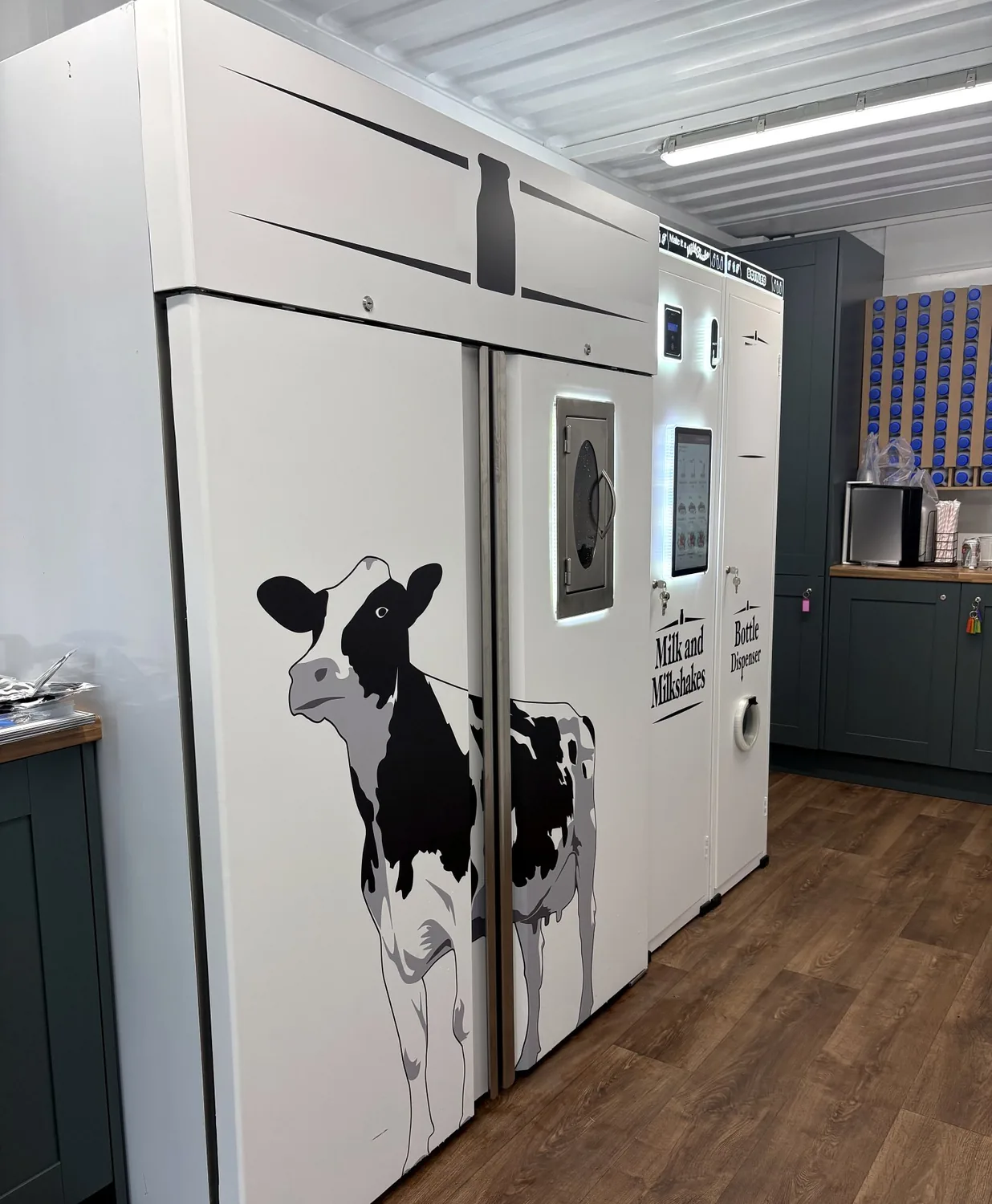 Milk and milkshake vending machine with a custom black-and-white cow wrap, installed in a farm shop